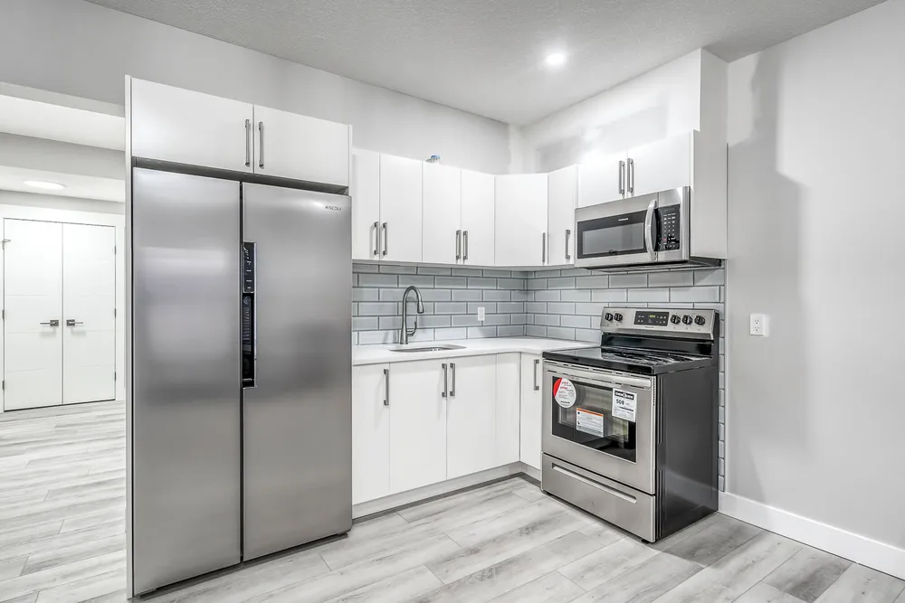 Unstyled white kitchen with stainless steel appliances and a tiled backsplash